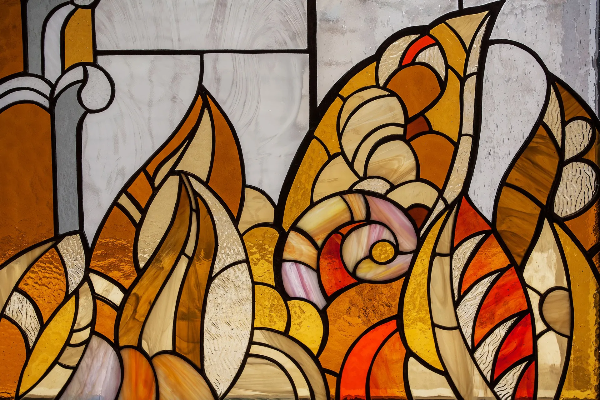 Warm amber and orange stained glass window with flame-like leaded shapes